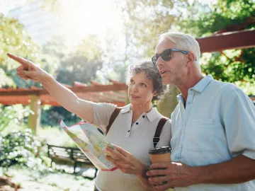 Couple of senior tourists using a city guide searching locations and pointing