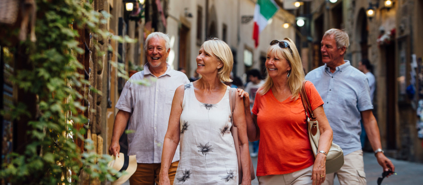 Four travellers walking a narrow Italian street in warm evening light